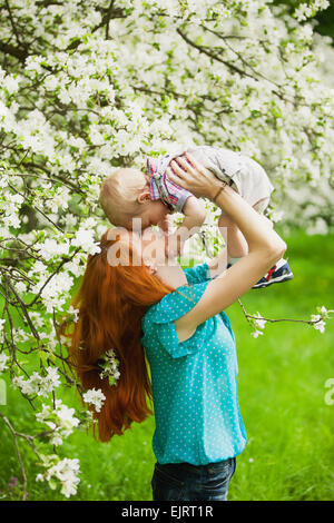 Portrait of happy happy mother and son jardin au printemps. Ils jouent et rient. Fleurs de pommiers. Notion de famille. Banque D'Images