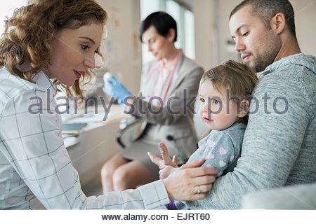 Les parents holding baby girl alors que pédiatre prépare la vaccination