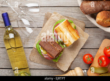 Deux sandwichs avec de la salade, du jambon, du fromage et des tomates avec du vin blanc sur la table en bois. Vue d'en haut Banque D'Images