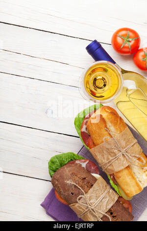 Deux sandwichs avec de la salade, du jambon, du fromage et des tomates avec du vin blanc sur la table en bois. Top View with copy space Banque D'Images