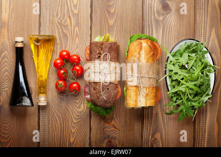 Deux sandwichs avec de la salade, jambon, fromage et tomates, salade et épices sur table en bois. Top View with copy space Banque D'Images