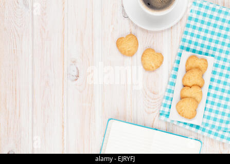 Café, biscuits en forme de coeur et le bloc-notes sur la table en bois blanc, avec copie espace Banque D'Images