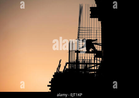 Travailleur de la construction d'ossature sur un chantier au coucher du soleil Banque D'Images