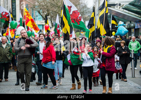 Personnes agitant des drapeaux et bannières welsh national marche dans les rues de prendre part à 'AberDewi' - St David's day saint patron de célébrations à Swansea au Pays de Galles, Royaume-Uni Banque D'Images