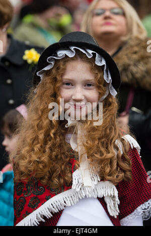 Un sourire heureux enfant jeune fille avec de longs cheveux gingembre rouge traditionnel gallois portant costume national robe à AberDewi «' - St David's day saint patron de célébrations à Swansea au Pays de Galles, Royaume-Uni Banque D'Images