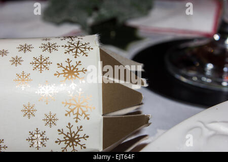 Tiré de Noël allongé sur une table avec une nappe de Noël sur le dessus avec une partie d'un verre de vin dans l'arrière-plan. Banque D'Images