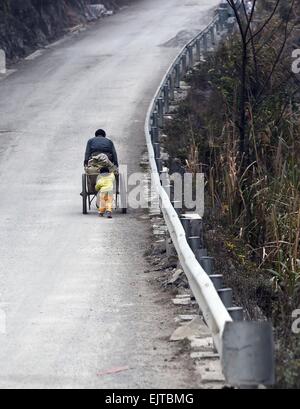 (150401) -- "LIUTONG, 1er avril 2015 (Xinhua) -- ?Un villageois tire un chariot transportant des ciments en Nongli Bansheng de village, canton sud-ouest de la Chine, région autonome Zhuang du Guangxi, le 13 février 2015. En raison de l'absence de plaine, la plupart des familles dans les zones montagneuses de l'ouest "Liutong construire leurs maisons sur les collines. Dans Qibainong Bansheng et comtés de "Liutong, gens de l'ethnie Miao ont vécu dans les montagnes pendant environ mille ans. Ils comptent sur la plantation des cors pour leur subsistance. Trois étages bâtiment guindée est l'architecture traditionnelle du style dans les deux comtés. Les gens Banque D'Images