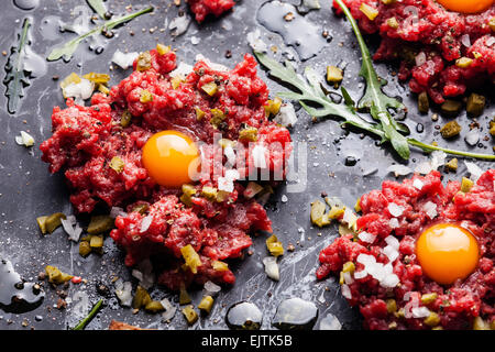 Tartare de boeuf cornichon oignon frais et sombre sur fond de marbre close-up Banque D'Images