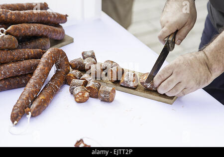 Saucisse de coupe avec un couteau, détail d'un chef de couper les aliments Banque D'Images