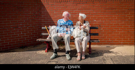 Couple de personnes âgées assis sur un banc, le front de Lowestoft, Suffolk, Angleterre. Banque D'Images