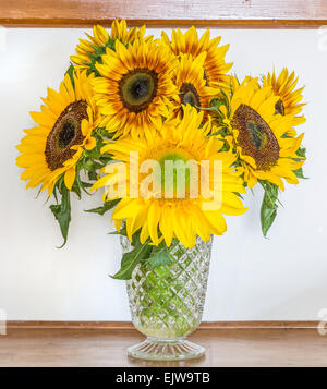 Un bouquet de tournesols dans un vase en verre orné de meubles anciens. Banque D'Images