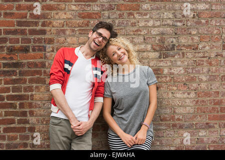 Portrait of couple standing against brick wall Banque D'Images