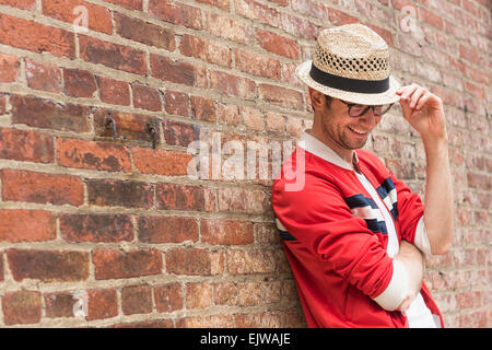 Portrait of mid adult man in front of brick wall Banque D'Images