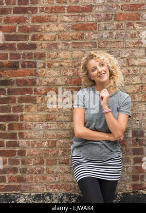 Portrait of young woman in front of brick wall Banque D'Images