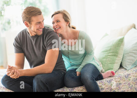 Smiling couple sitting on bed Banque D'Images