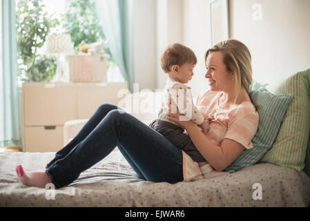 Mère heureuse de jouer avec peu de son (2-3 ans) on bed Banque D'Images