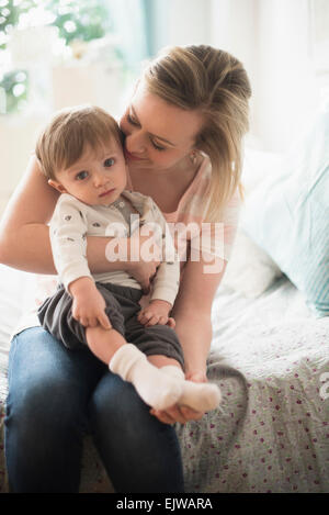 Mère assise avec peu de son (2-3 ans) on bed Banque D'Images