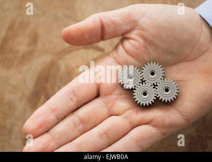 Close up of man's hand holding metal cogs Banque D'Images