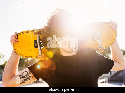 USA, Floride, West Palm Beach, Man holding skateboard sur ses bras Banque D'Images