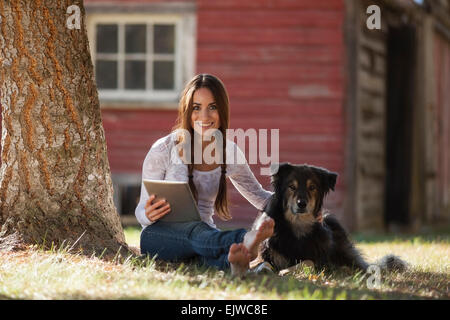 USA, Montana, Whitefish, Woman with dog under tree Banque D'Images