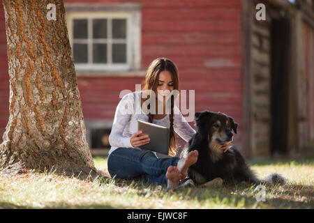 USA, Montana, Whitefish, Woman with dog under tree Banque D'Images