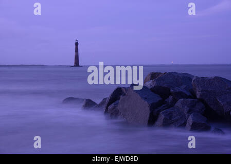 USA, Caroline du Sud, Folly Beach, Morris Island, roches côtières et le phare qui se profile comme le crépuscule Banque D'Images