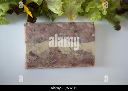 Jarret fumé et terrine de foie gras avec salade et piccalilli servi sur une plaque blanche. Banque D'Images