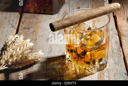 Verre de whisky avec de la glace et de l'orge sur les épillets table en bois Banque D'Images