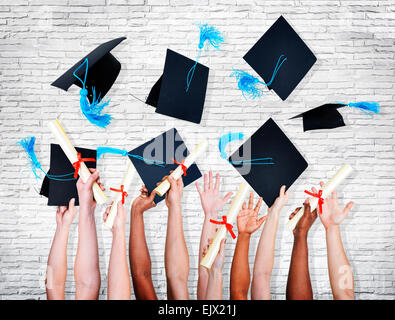 Groupe de mains holding diplomas and throwing graduation chapeaux en l'air. Banque D'Images