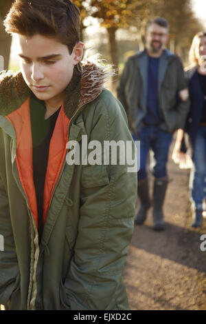 Teenage Boy Walking in Country Road, Parents en arrière-plan