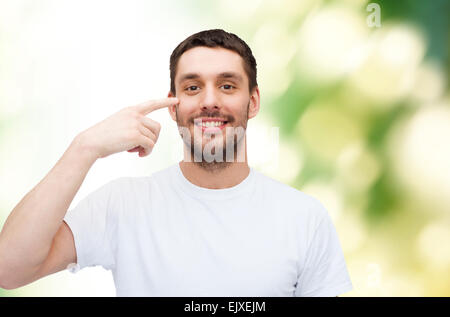 Smiling young man pointing pour les yeux Banque D'Images