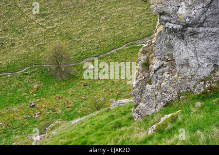 Regardant vers le bas, sur le sentier menant à Lathkill Dale, Derbyshire. Rocher calcaire à l'avant-plan. Aubépine à côté du chemin. Banque D'Images