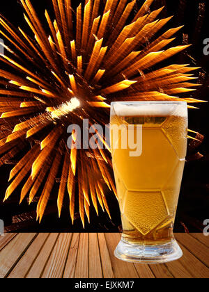 Verre de bière sur la table en bois doré sur fond d'artifice. Banque D'Images