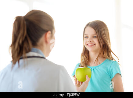 Femme médecin de donner à apple smiling little girl Banque D'Images