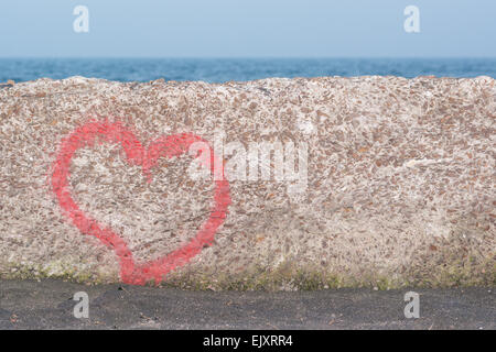 Coeur rouge peint à la bombe sur le mur en arrière-plan de la mer Banque D'Images