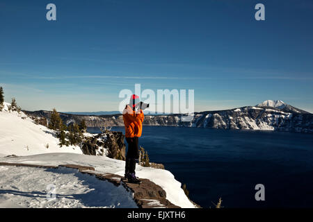 OREGON - Une skieuse de s'arrêter pour prendre une photo le long du bord de lac de cratère dans la région de Crater Lake National Park. Banque D'Images