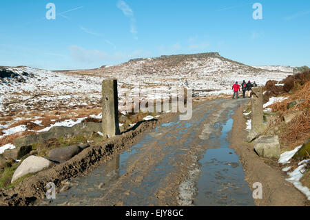 Les promeneurs sur une piste boueuse avec Carl Wark colline au loin. Près de Hathersage, Peak District, Derbyshire, Angleterre, RU Banque D'Images