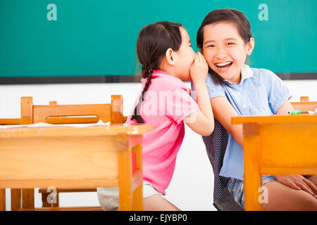 Happy little girls whispering et partage un secret en classe Banque D'Images