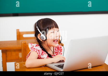 Happy little girl learning computer in classroom Banque D'Images