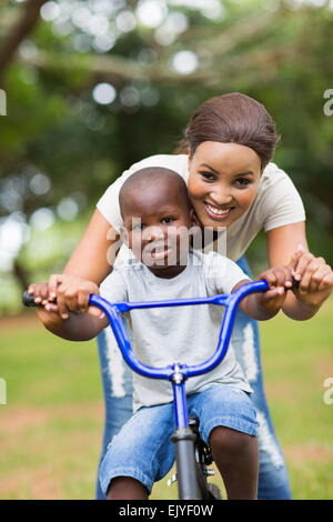 Belle Mère de l'Afrique de l'enseignement son petit fils à faire du vélo au parc Banque D'Images