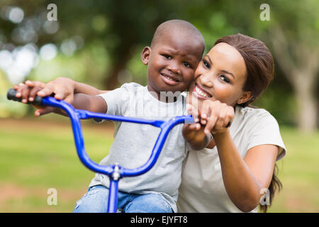 Prendre soin African American Woman aider son fils à faire du vélo dans la région de park Banque D'Images