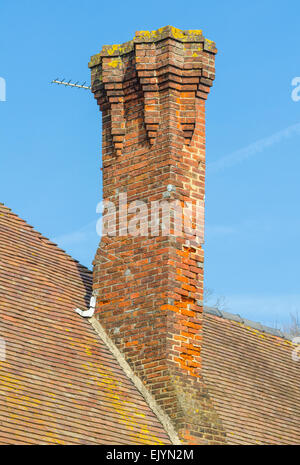 Grande cheminée en brique rouge sur un toit en tuiles rouges en Angleterre, Royaume-Uni. Banque D'Images