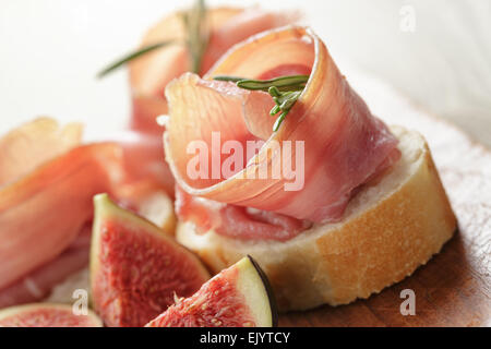 Des canapés avec jambon et figues sur planche de bois Banque D'Images