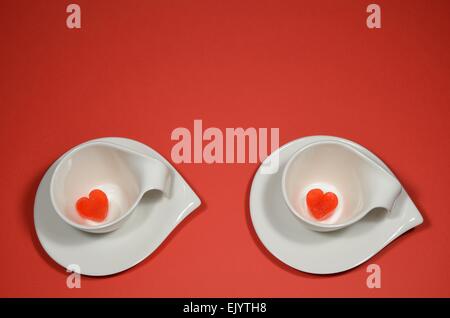 Deux tasses avec coeur des cubes de glace sur fond rouge Banque D'Images