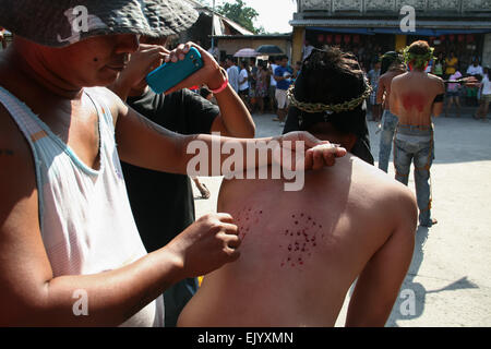 San Fernando, aux Philippines. 06Th avr, 2015. Un assistant pour les pénitents slice ouvrir la peau pour démarrer le flux sanguin pour l'auto flagellation au cours de la célébration du Vendredi Saint à Pampanga, au nord de Manille. Crédit : J Gerard Seguia/Pacific Press/Alamy Live News Banque D'Images