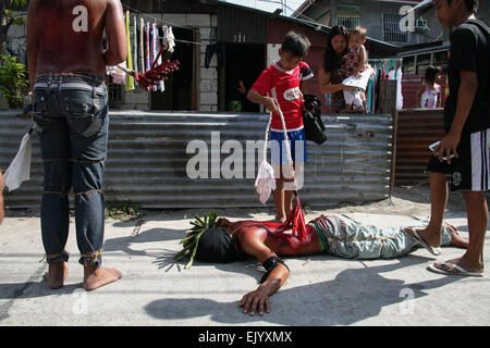 San Fernando, aux Philippines. 06Th avr, 2015. Un flagellant fouettée par un membre de sa famille, comme il s'arrête en face de sa maison, de demander pardon à sa famille lors de la célébration du Vendredi Saint à Pampanga, au nord de Manille. Crédit : J Gerard Seguia/Pacific Press/Alamy Live News Banque D'Images