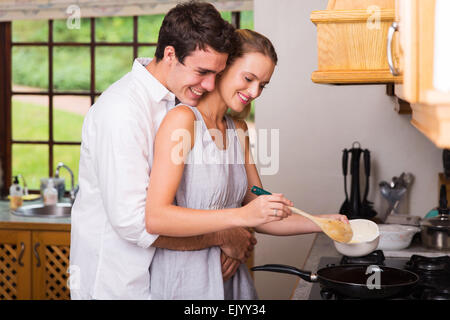 Jeune homme romantique petite amie en serrant elle cuisine pour le petit déjeuner Banque D'Images