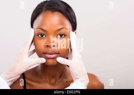 Médecin faisant vérification de la peau sur la femme africaine avant la chirurgie cosmétique Banque D'Images