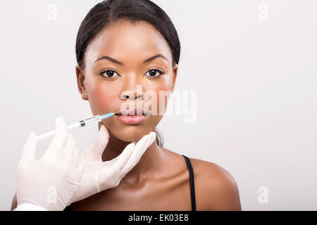 Jolie petite fille africaine qui reçoivent l'injection cosmétique sur ses lèvres Banque D'Images