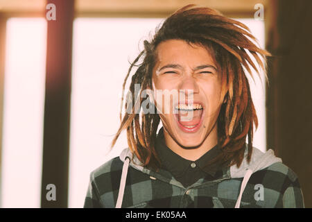 Portrait de jeune homme avec des cheveux rasta et skateboard dans un concept de vie filtre appliqué à chaud Banque D'Images